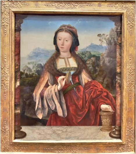 A gilt-framed Renaissance painting of Mary Magdalene in a red gown, her alabaster ointment jar on the ledge beside her