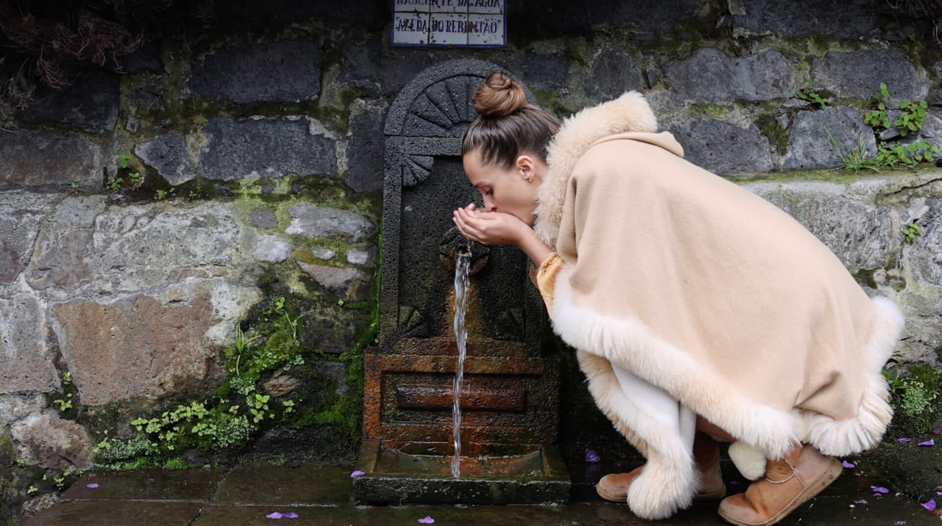 A sacred spring pouring from mossy stone
